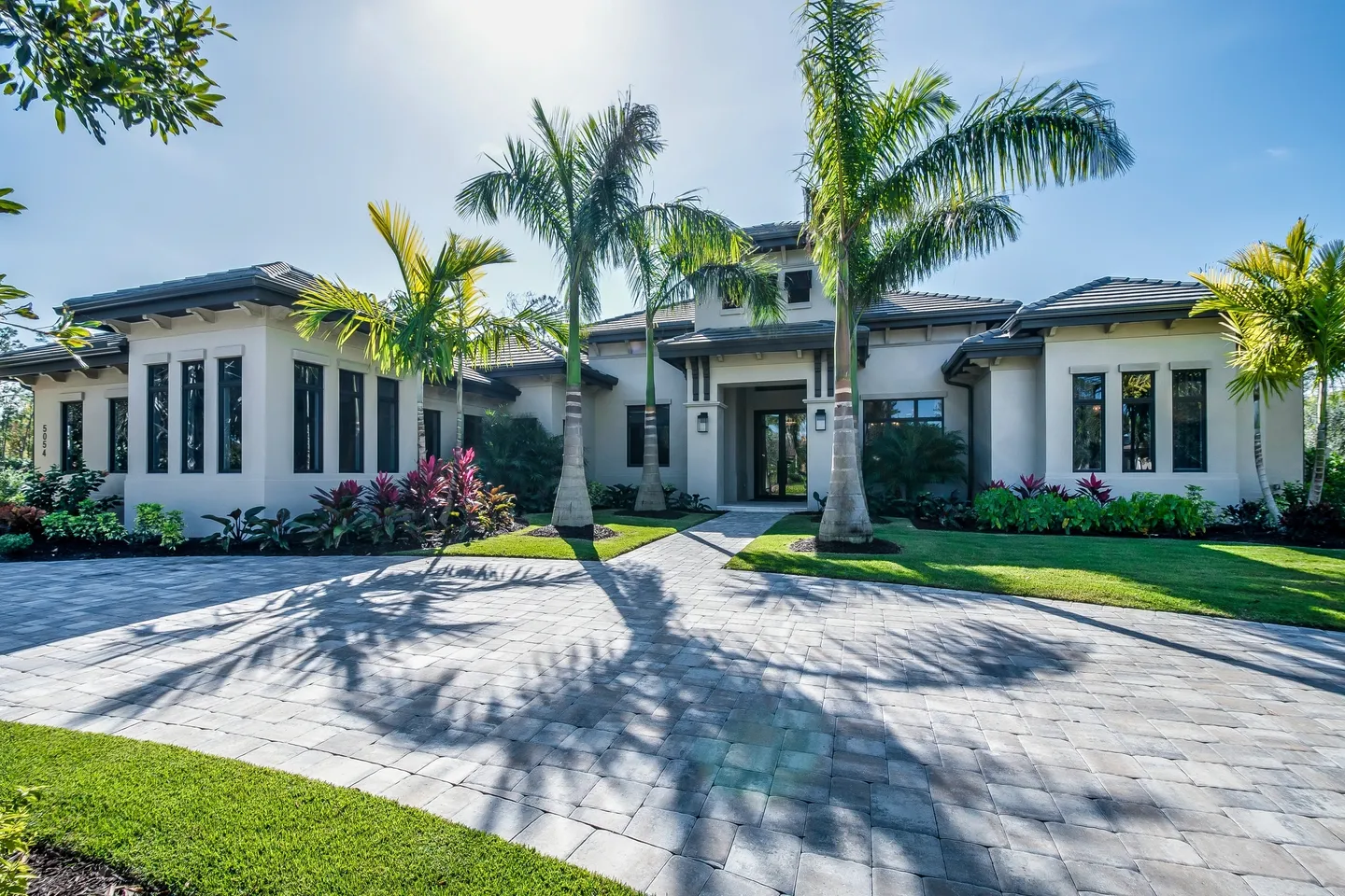 A large white house with palm trees in the front yard.